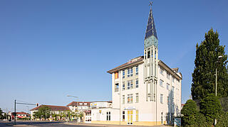 Aufnahme des Gebäudes Achillesstr. mit dem markanten zieselierten an einen Kirchturm erinnernden Turmbau mit Solarkollektoren.