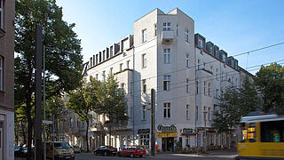 Eckhaus Langhansstraße, im Vordergrund fährt eine Straßenbahn.