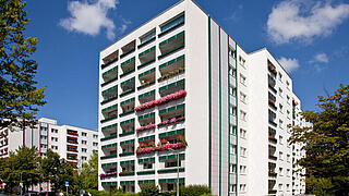 Außenaufnahme zeigt ein achtgeschossiges Hochhaus mit teilweise üppig und bunt bepflanzten Balkonen im Bernshausener Außenring.