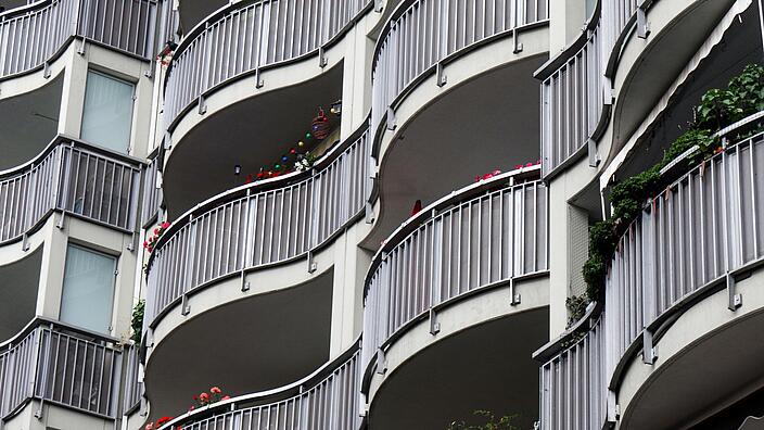 Aufnahem von unten: Eine Fassade mit wellenförmigen Balkonen und ebenfalls wellenförmigen Balustraden aus Metallstreben.